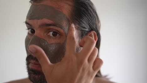 man using a clay mask on his face