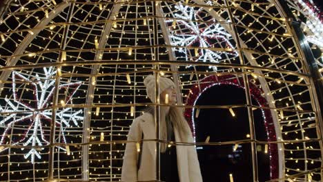 happy woman among christmas decorations and lights at night