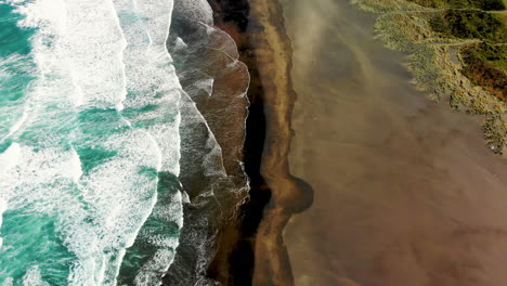 sorprendente rivelazione aerea di lion rock sulla famosa spiaggia di sabbia nera di piha, in nuova zelanda