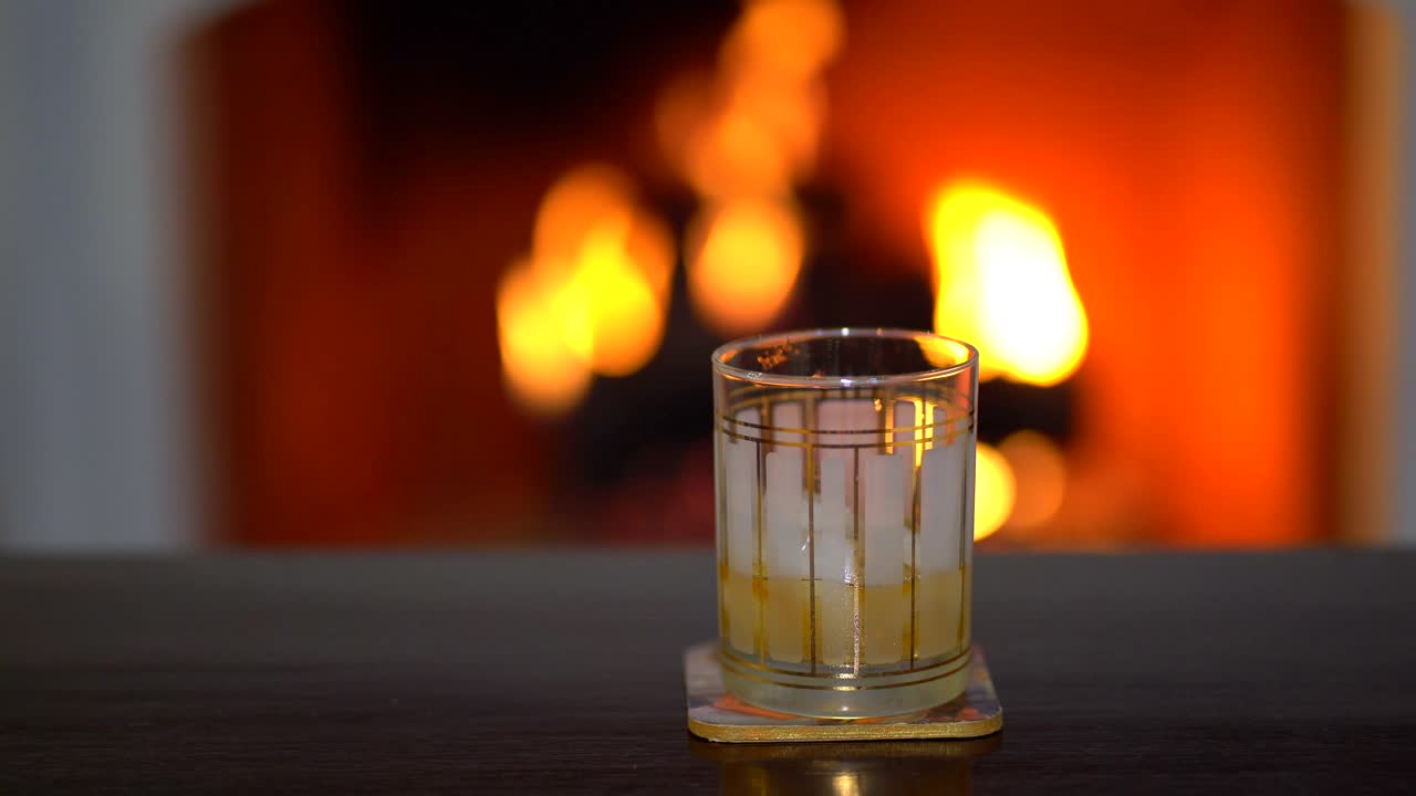 Taking glass of whiskey . Drink and fireplace background.