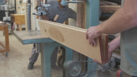 two carpenters resaw white oak timber length using bandsaw
