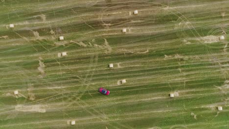 vehicle driving circular maneuvers on rural farm field with scattered hay bales