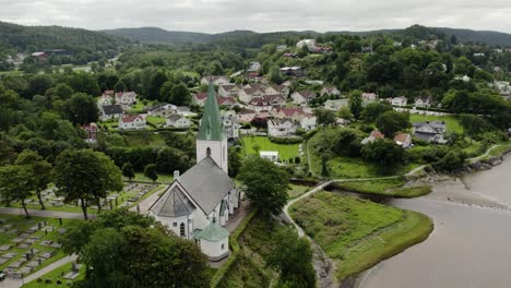 Ljungs-Kyrka-church-of-Ljungskile-Parish-Bohuslan-Sweden-overlooks-estuary-in-quaint-village,-Aerial-orbit