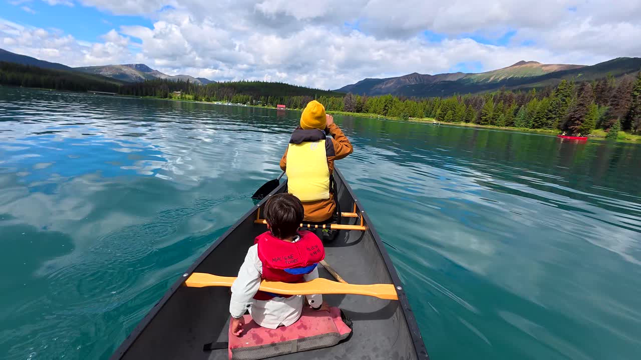 Personen beim Kanufahren auf einem See mit Bergblick
