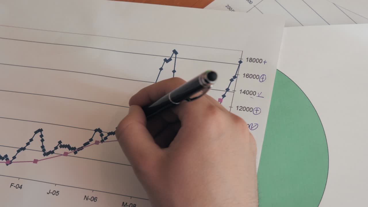 Close up of hand of young succesful man writing on the economy statistics