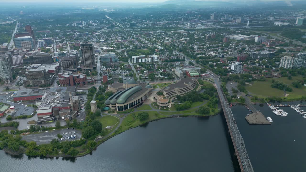 overhead summer perspective drone view of the Canadian History Museum's Indigenous Experiences buildings situated along the waterfront of the Ottawa river calm water next to the Alexandra bridge brg