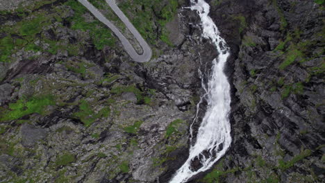 Top-down-aerial-shot-of-the-Trollfossen-waterfall-cascading-down-a-cliff-into-the-Tverelva-river-in-Norway