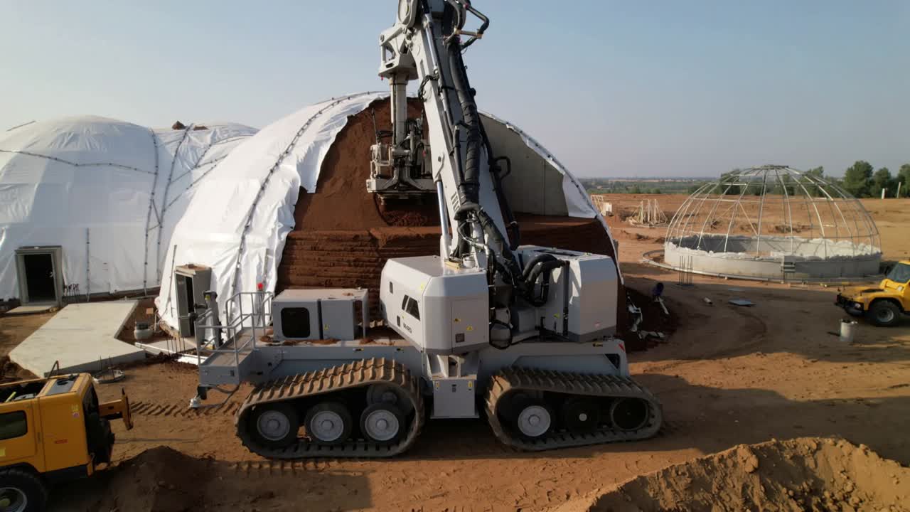 Lowering after signal, tracked excavator scraping dome at worksite, forming stepped layers
