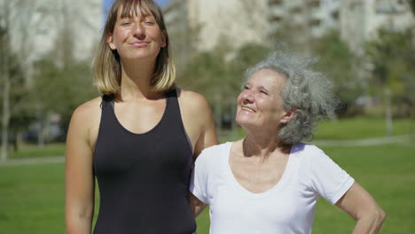 two mature women embracing and talking to camera