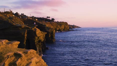 turista mujer sentada y viendo la puesta de sol en los acantilados costeros de la puesta de sol, san diego, california