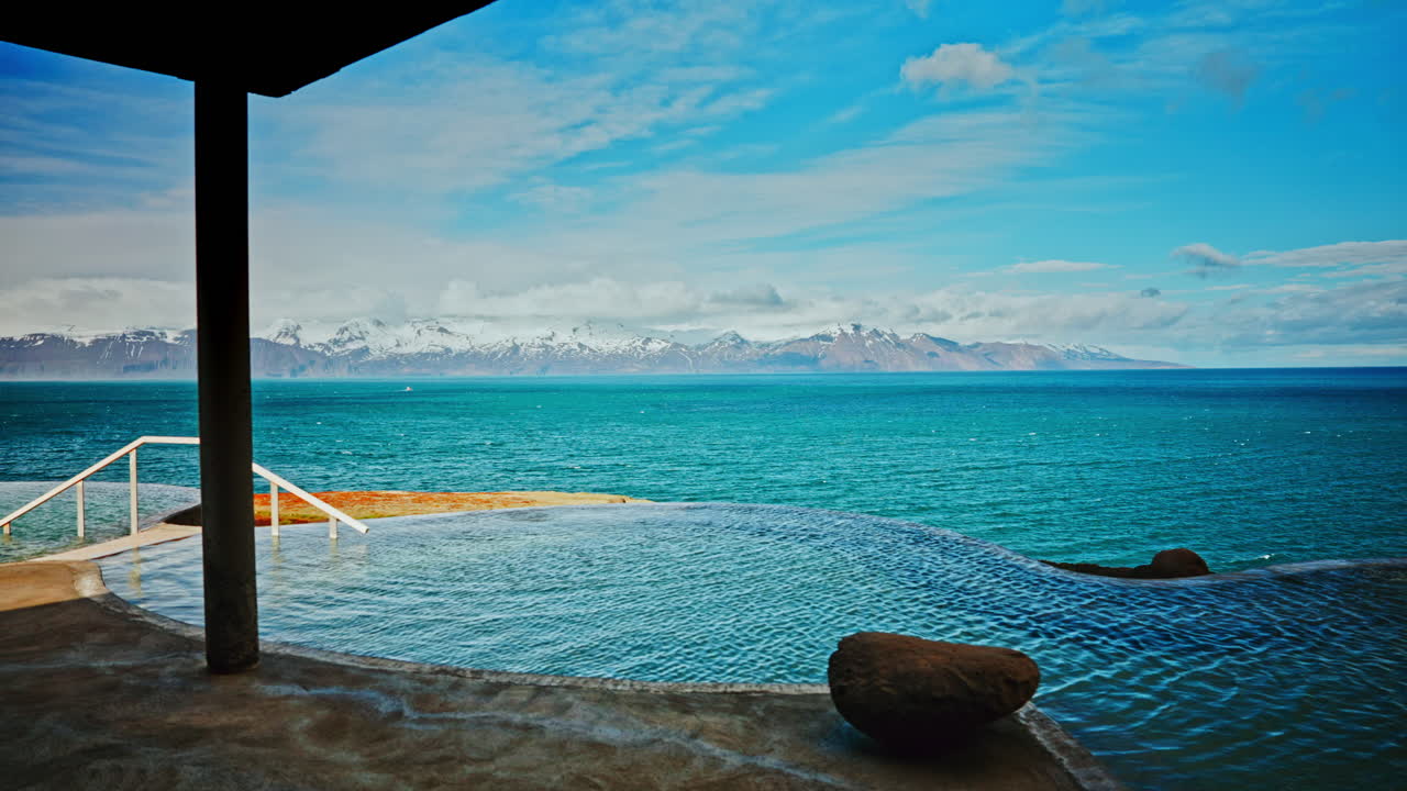 야외 아이슬란드 수온 스파는 북극 해와 웅장한 눈 인 산맥의 환상적인 전망을 가지고 있습니다.