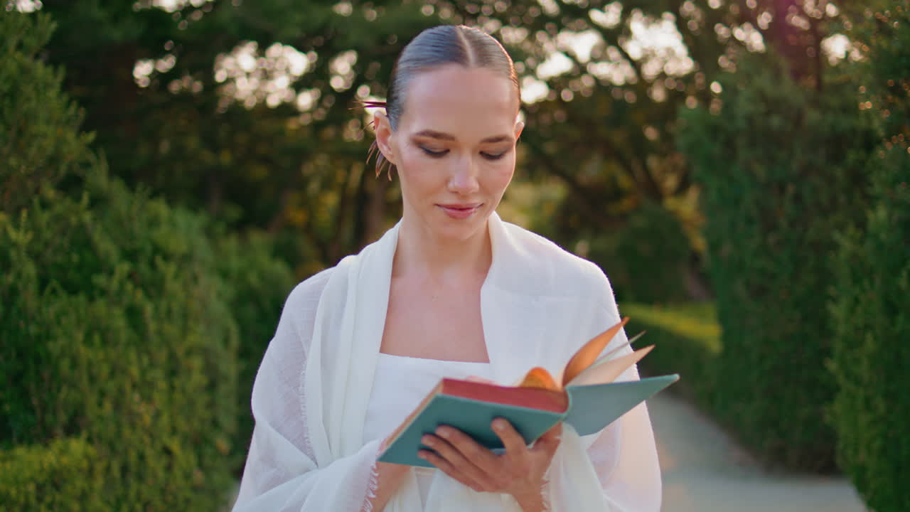 책을 들고 미소 짓는 여자가 아름다운 공원 골목에서 혼자 고 있습니다.