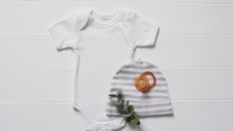 video of white baby grow, hat and dummy with copy space on white background