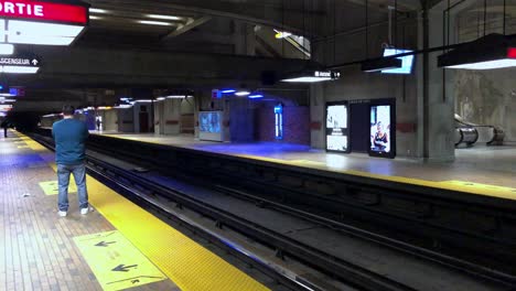 a quiet underground subway platform with only two commuters waiting for a train.