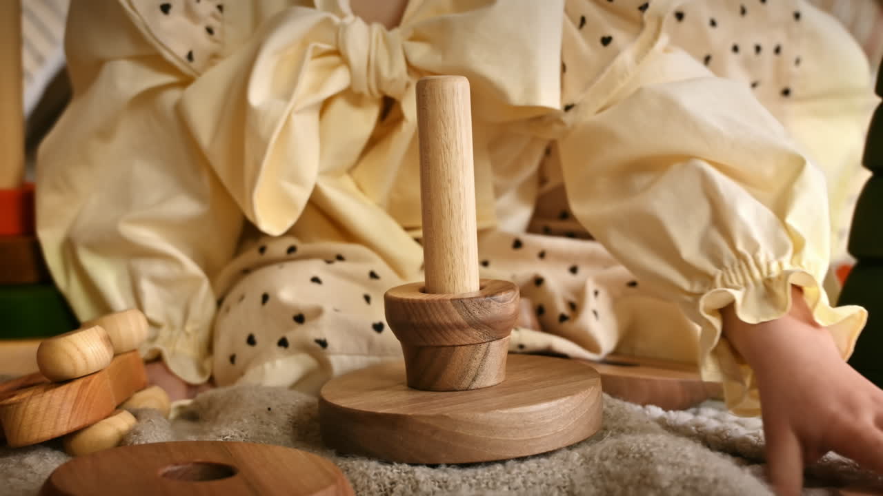 Little girl's hands playing with a wooden stacking jug. Ecological and sustainability concept