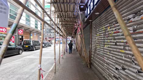 pedestrians navigate scaffolding on a busy street