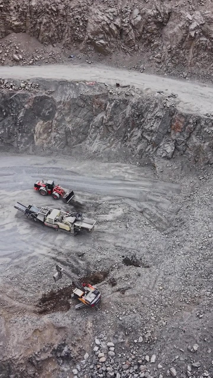 Quarry site with vehicles and rocks in operation during the day