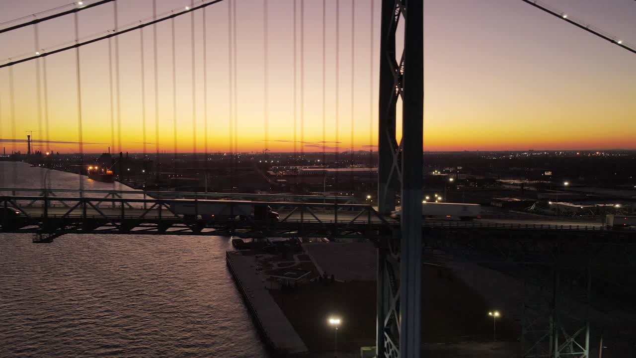 미시간 주 디트로이트에서 디트로이트 강을 건너 일몰에 대사 다리를 운전하는 트럭