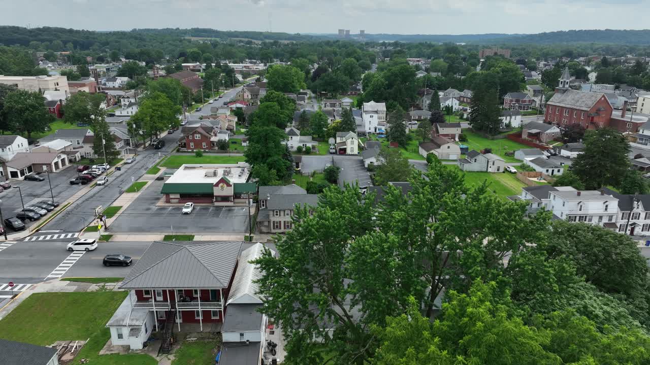 Cloudy morning in American town. Aerial flyover. Cars on street. Historic houses and homes with church in background. Middletown, Pennsylvania. Grass in yards