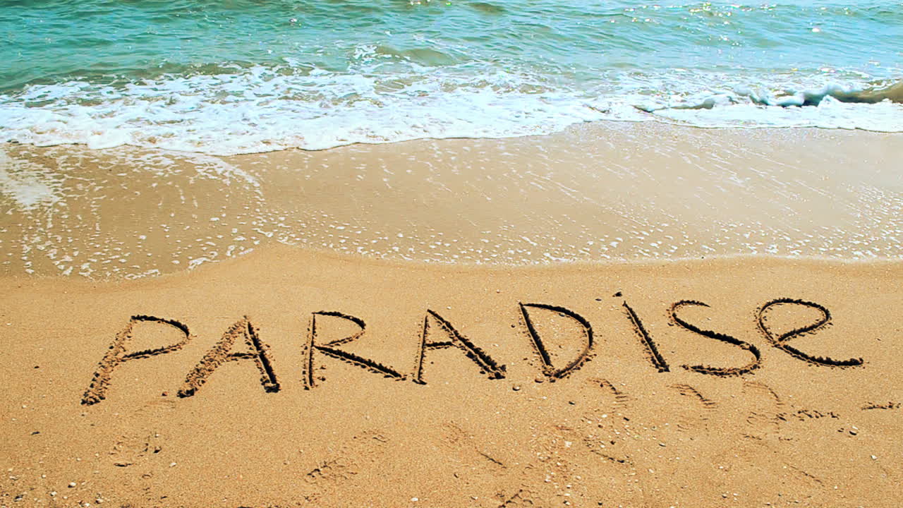 Inscription paradise on sand. Shooting on the beach