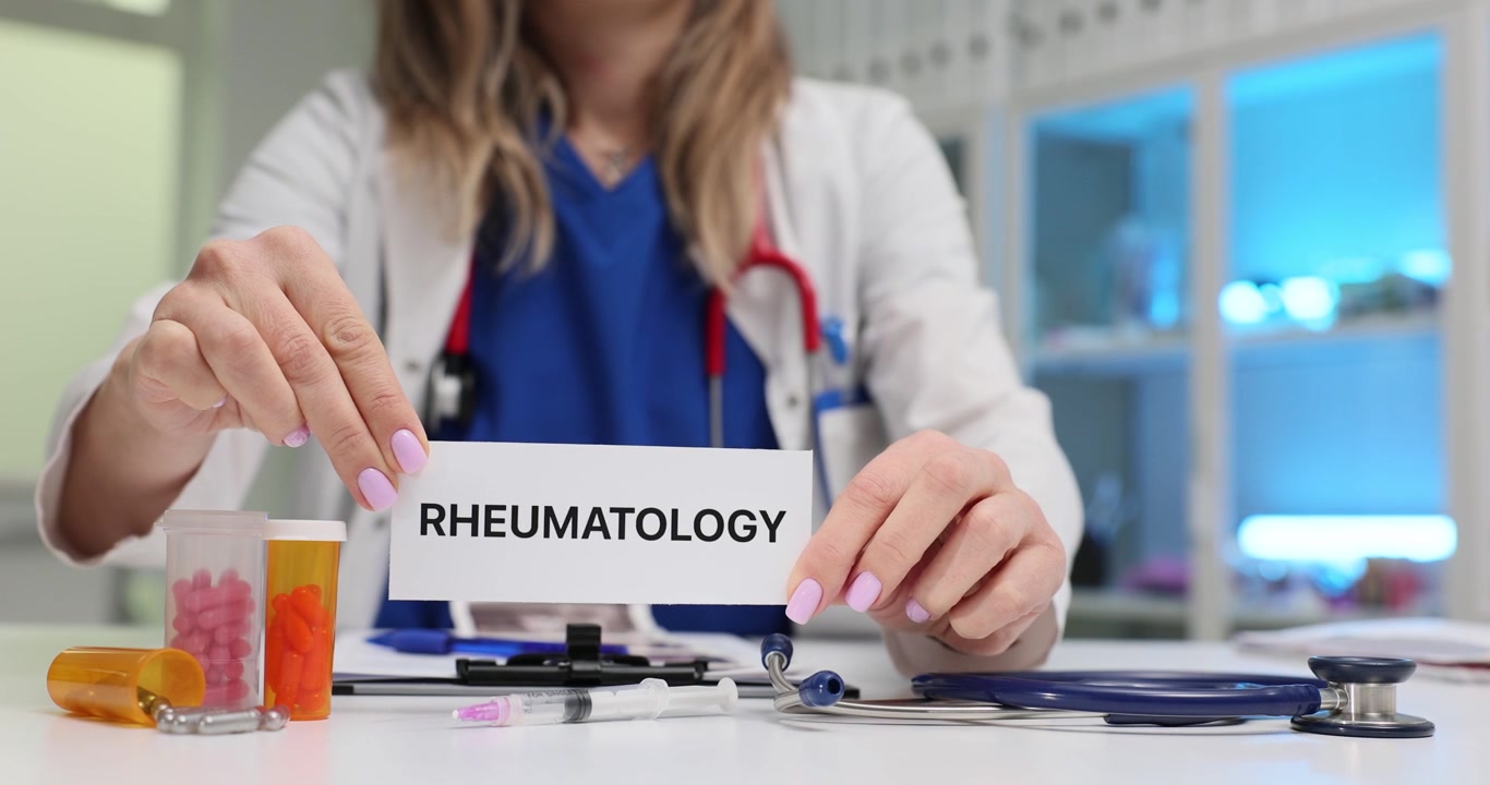 Woman doctor shows word rheumatology on paper sheet