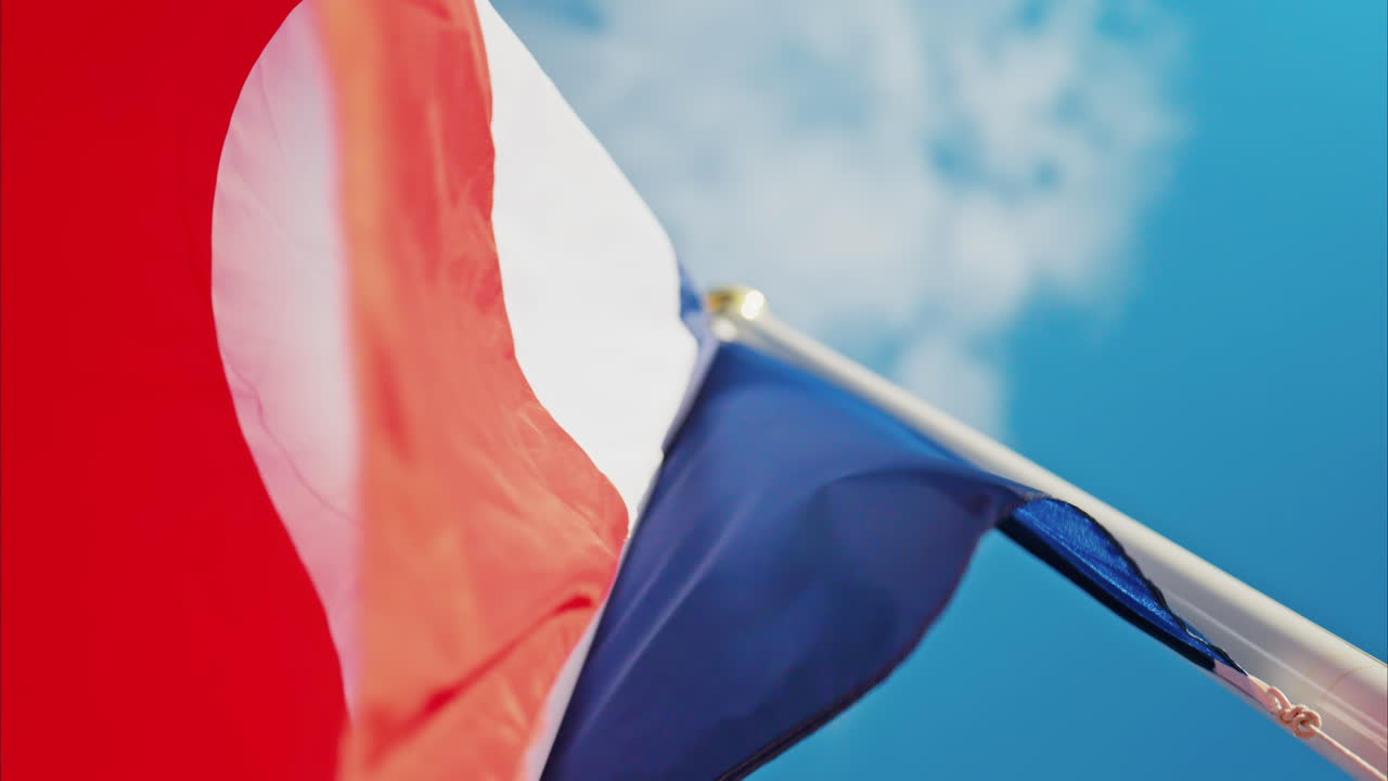 Close up of the French flag waving with the blue sky on the background