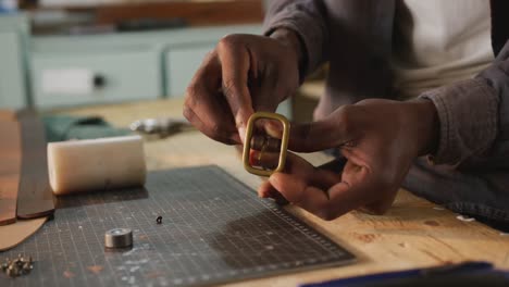 hands of african american craftsman using tool to make a belt in leather workshop