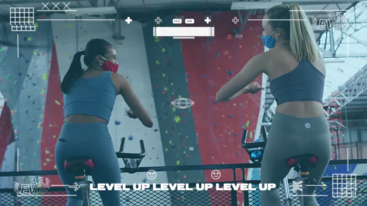 체육관에서 정지 자전거에서 운동하는 동안 팔꿈치를 만지는 두 여성에 대한 게임 인터페이스