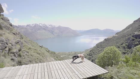girl performing yoga on summer day overlooking blue lakes and mountain ranges in queenstown new zealand.