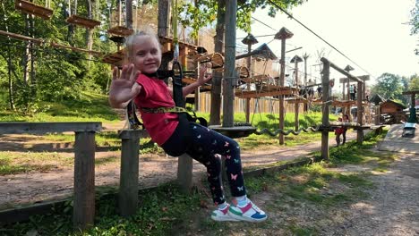 happy little girl playing in tarzan attraction on playground in amusement park