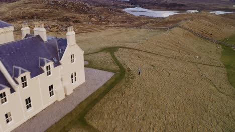 Drohnenaufnahme-Eines-Geigers,-Der-Seine-Geige-Spielt,-Neben-Einem-Landsitz-Auf-Der-Isle-Of-Lewis,-Äußere-Hebriden-Von-Schottland,-Vereinigtes-Königreich