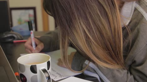 mujer escribiendo algo en una página con un marcador