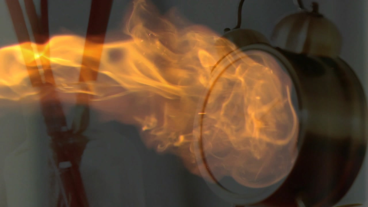 Orange plume appearing near brushes growing and flowing right wrapping clock and making reflections