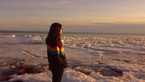 young-women-wearing-pride-colors-jacket-on-a-Rock-in-the-middle-of-a-frozen-lake