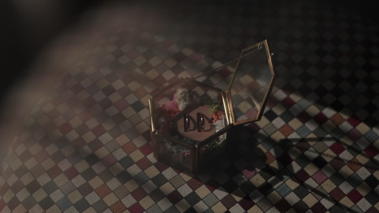 open hexagonal glass wedding ring box on a mosaic floor, lit by soft sunlight