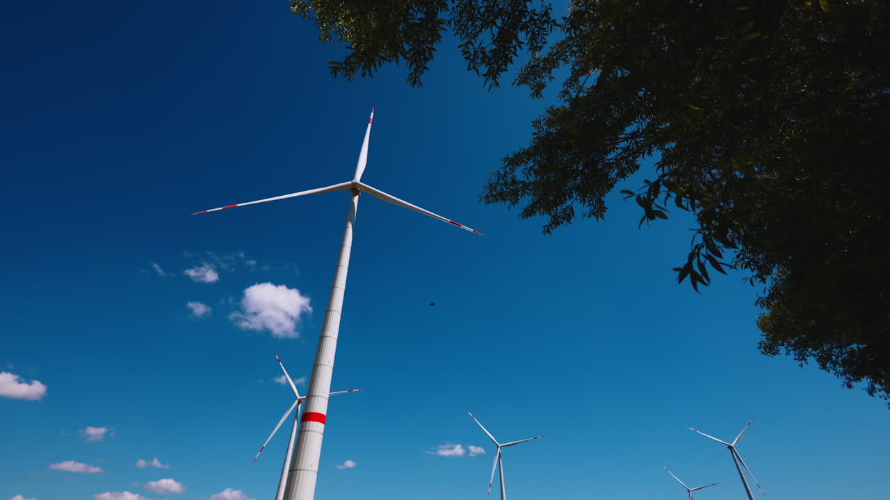 Wind turbines rotating slowly in the wind in beautiful blue sky. Energy production. Low angle view.