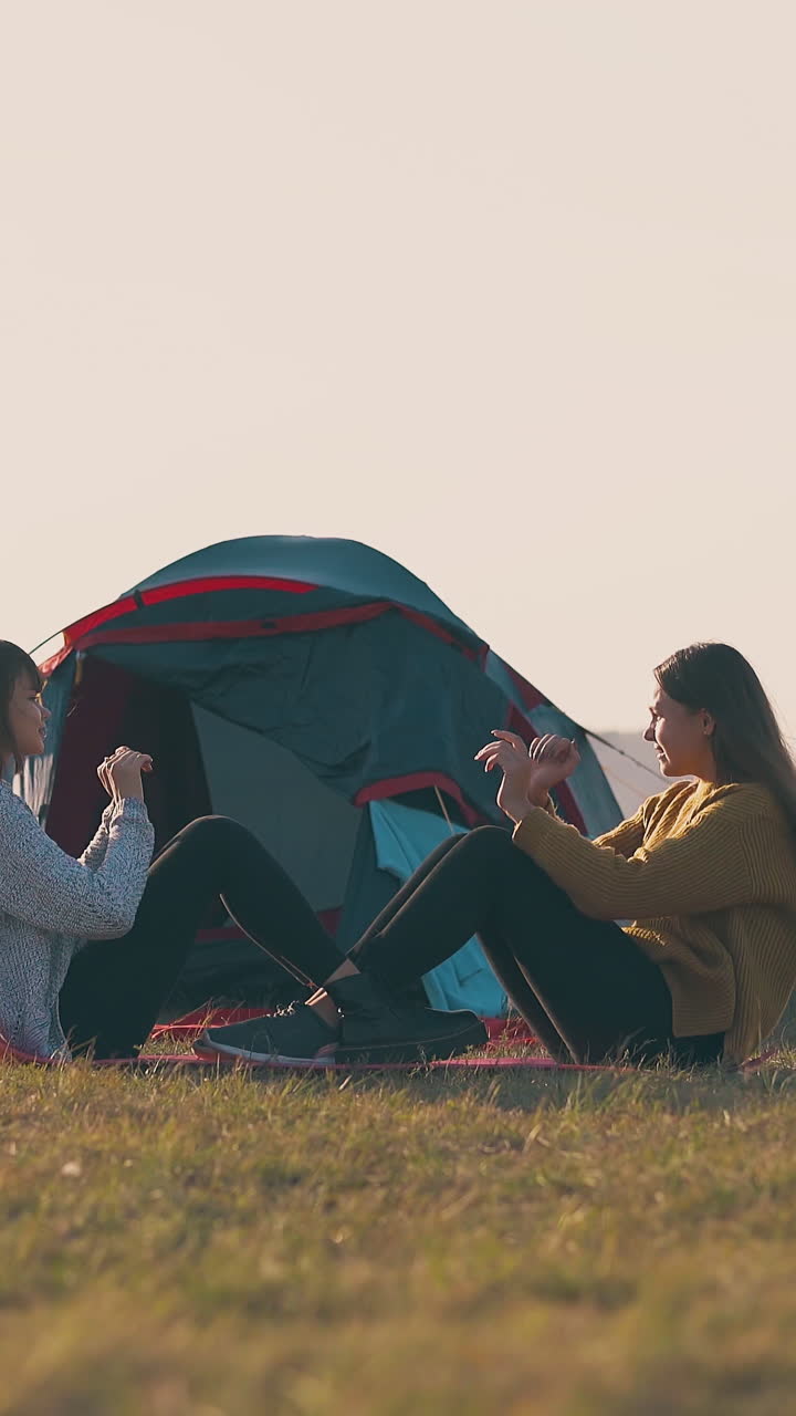 girl tourists do abs exercises clapping hands in comfortable camp with tent on hill river bank at sunset