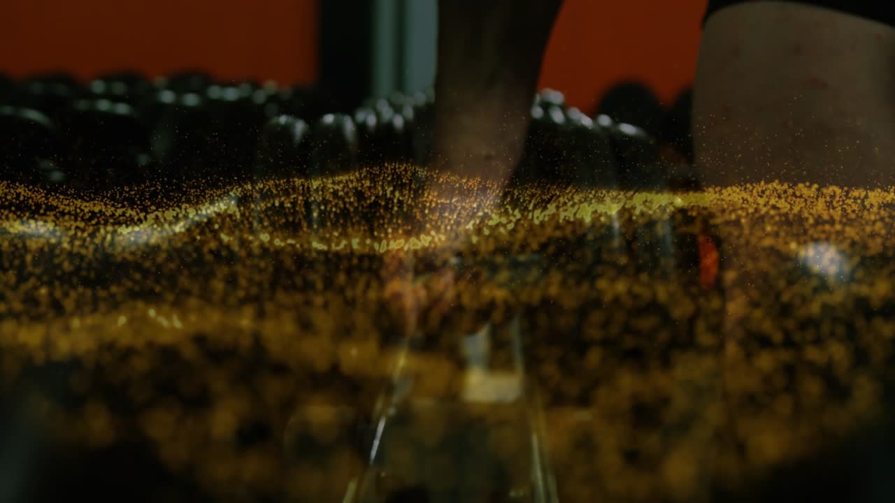 Hand entering frame, sliding over weights as gold dust rising, gripping, lifting weight for workout