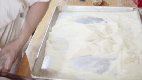 a pastry chef tosses freshly baked pastries in sugar or flour on a tray to coat them