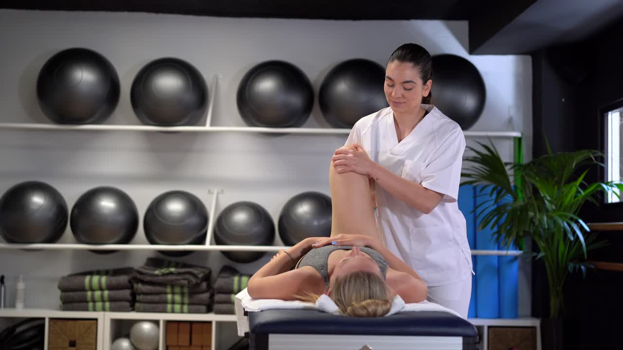Delight female physiotherapist massaging leg of crop woman