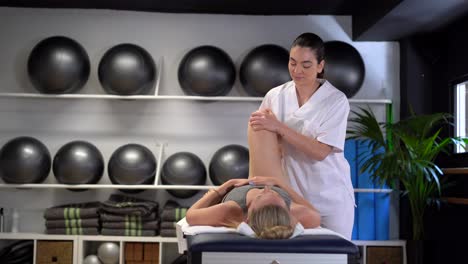 deleitar a la fisioterapeuta masajeando la pierna de la mujer de la cosecha