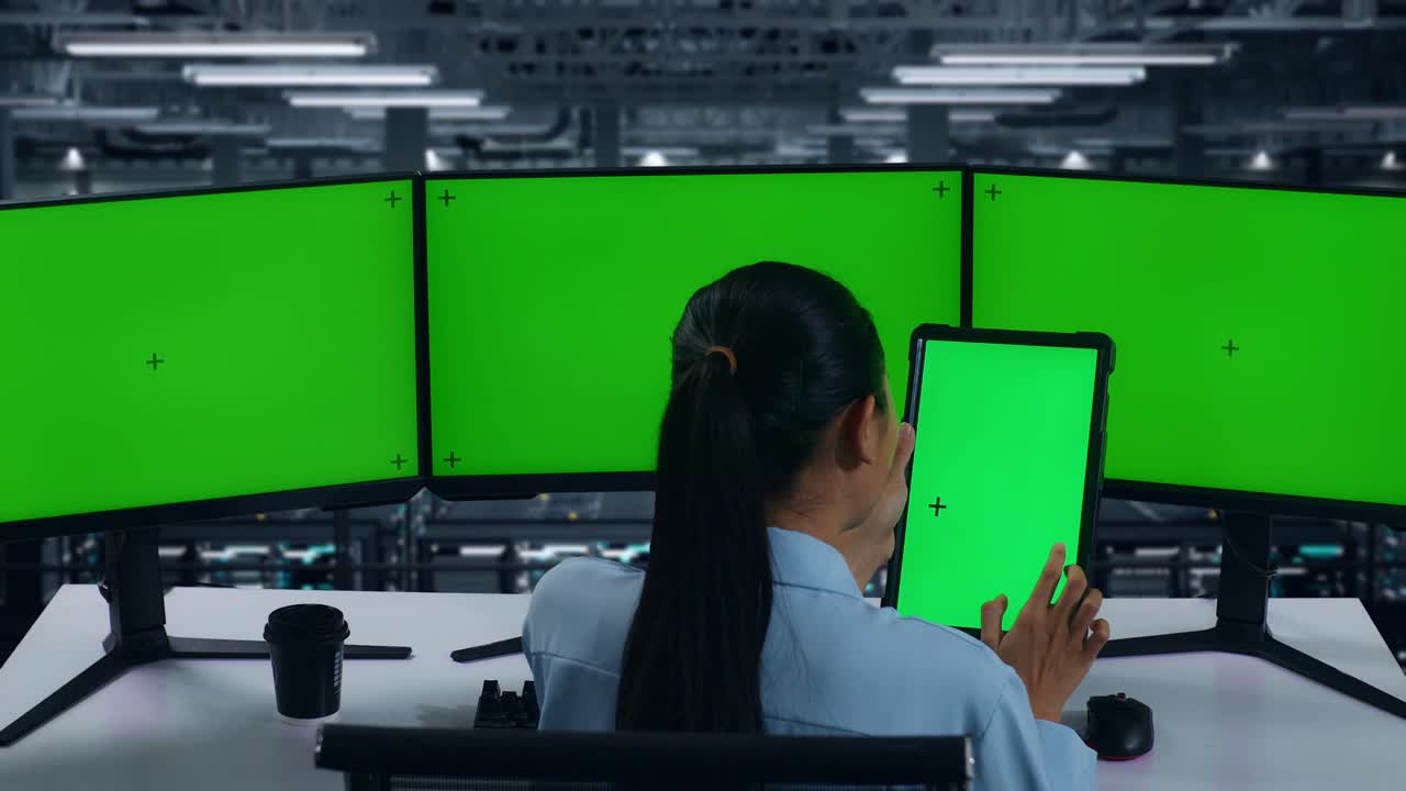 태블릿과 여러 컴퓨터 모니터로 작업하는 아시아 여성의 뒷모습 데이터 센터에서 모의 녹색 화면