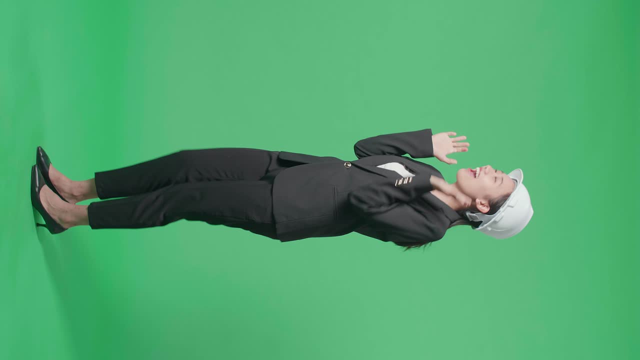 Full Body Side View Of Smiling Asian Female Engineer With Safety Helmet Dancing In The Green Screen Studio