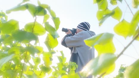 photographer holding camera points and shoots in nature park scene, bright sky, dreamy effect