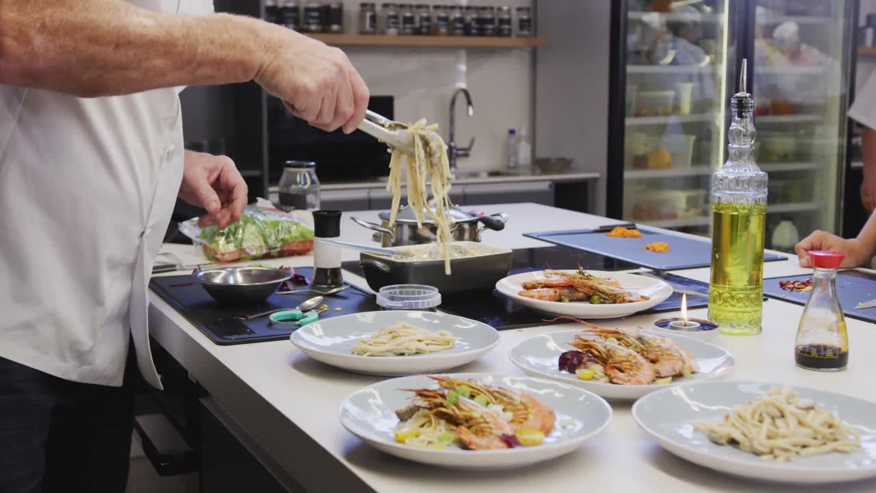 레스토랑 주방에서 레스토랑  ⁇ 옷을 입은 백인 남성 요리사, 접시에 음식을 넣고