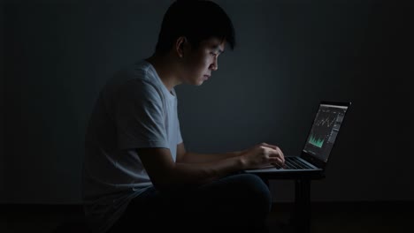 focused individual analyzing data on laptop during nighttime, illuminated by screen light, showcasing deep concentration and digital engagement