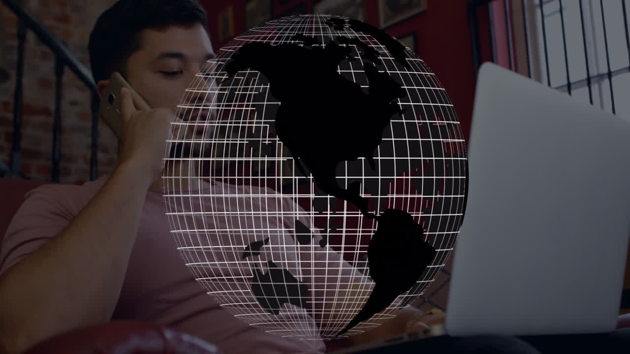 Working on laptop, man with globe animation overlaying screen in office