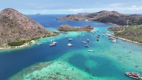 labuan bajo's waecicu beach, turquoise water and boats docked along the shore, aerial view