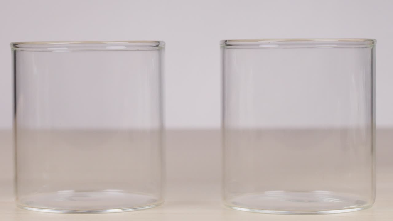 Two glasses of cold and hot water with bubbles, neutral background, static camera, even lighting
