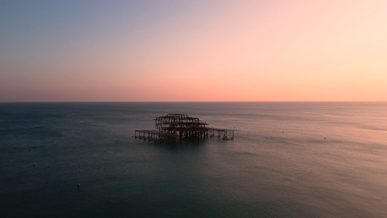 Brighton West Pier-ruiner i skumringen over roligt hav med pastel solnedgangshimmel – dronefoto